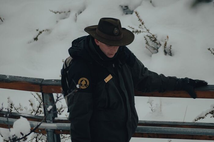 Park ranger in winter gear standing outdoors on a snowy day, representing jobs that can make 6 figures.