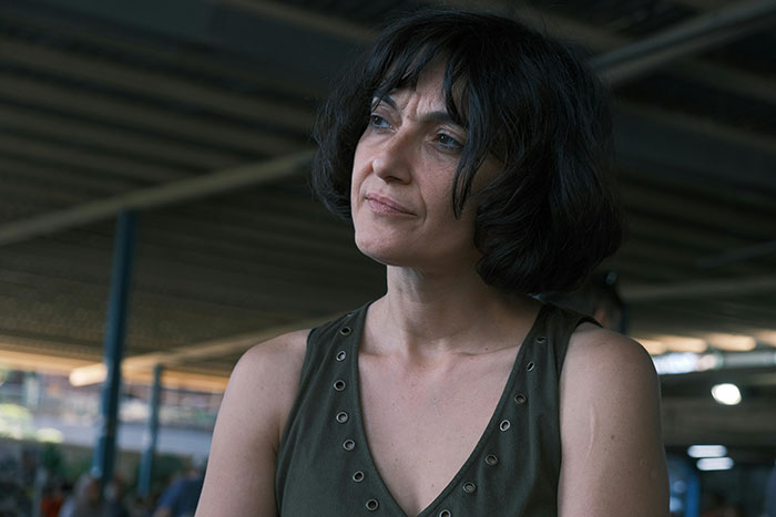 Woman with dark hair wearing a sleeveless top, looking thoughtful in a dimly lit setting, depicting manipulative mom story drama. - 19