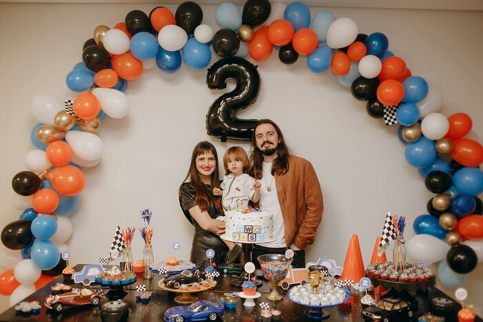 Family celebrating child's second birthday with colorful balloons and toy cars, reflecting trends leading to overconsumption. - 20