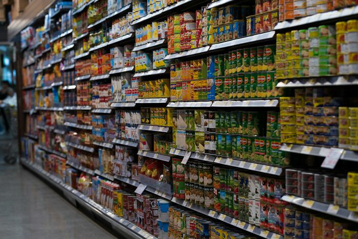 Grocery store aisle with shelves stocked full of packaged food highlighting the global food waste crisis.