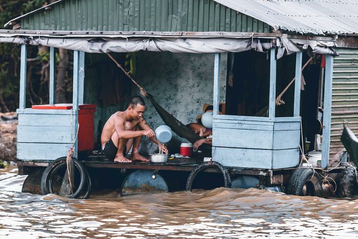 Two men on a floating house on murky water, demonstrating calm moments amid uncertain surroundings and red flags. - 6