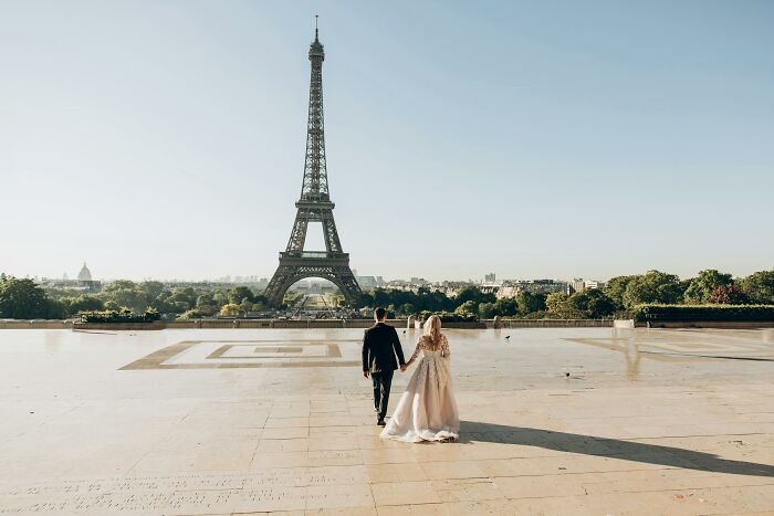 Couple walking hand in hand near the Eiffel Tower, a romantic setting perfect for using pickup lines.