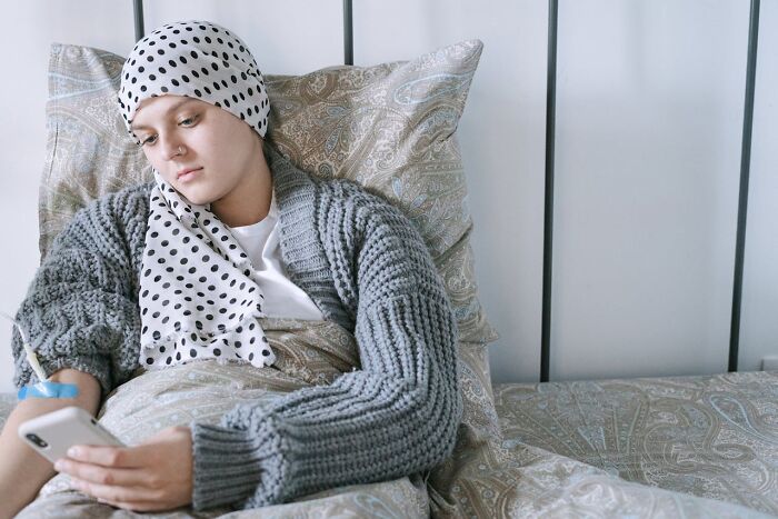 Young woman in bed wearing a headscarf, looking at her phone with a sad expression, reflecting on toxic friendships. - 38