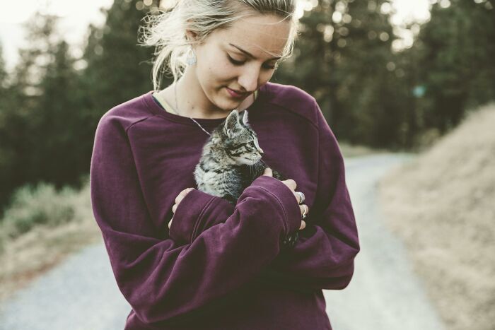 Woman holding a cat outdoors, representing the story of a cat-sit during a family emergency and the fight to get the pet back. - 5