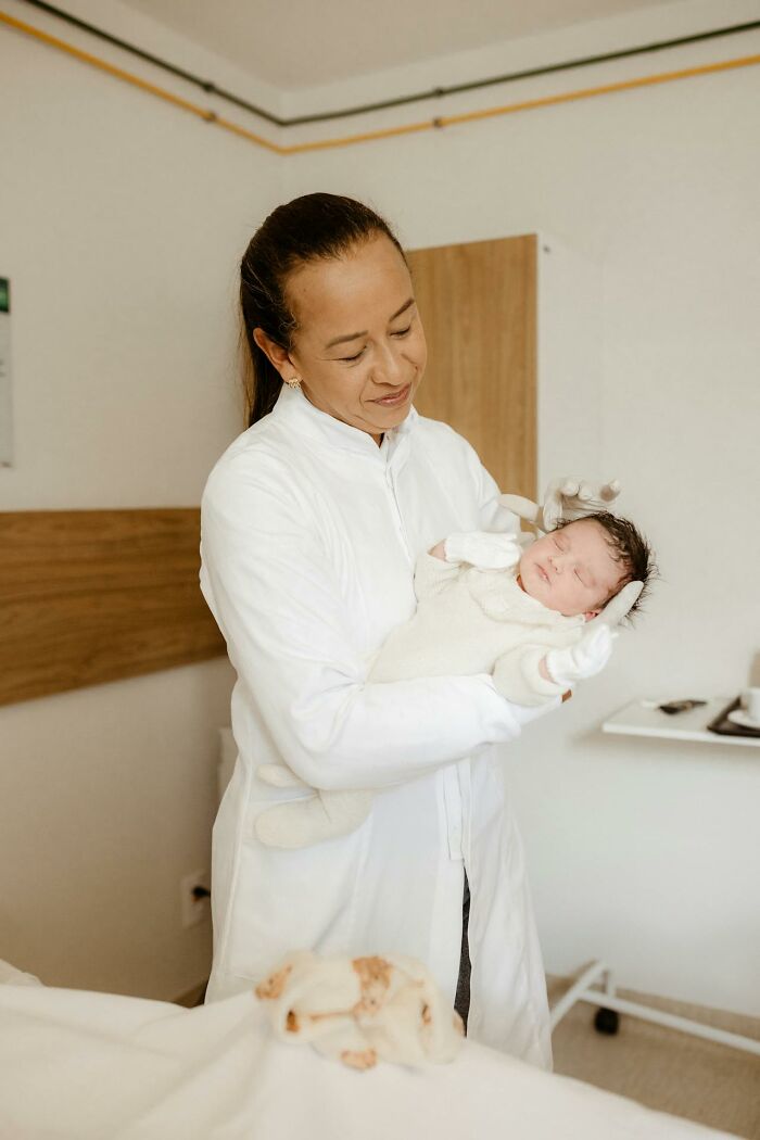 Healthcare professional holding a newborn baby in a medical room, illustrating entitled patients demanding special treatment.