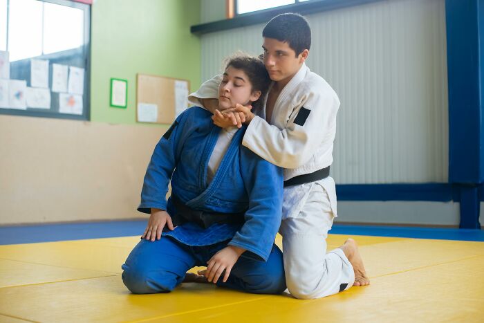 Dos personas practicando judo en un dojo, mostrando una técnica de control, ilustrando un dilema moral en acción diaria.