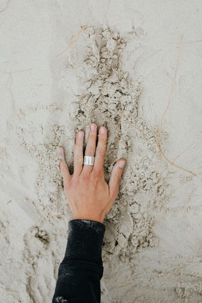 Hand with ring pressing into textured sand, illustrating survival tips concept for survival tips SEO keyword.