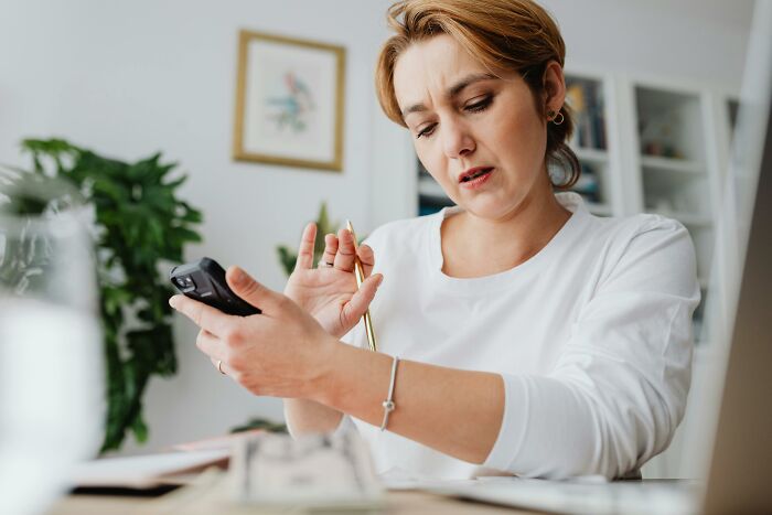 Woman holding remote control and pen, focused on solving a Hollywood movie challenge with visual hints at home.