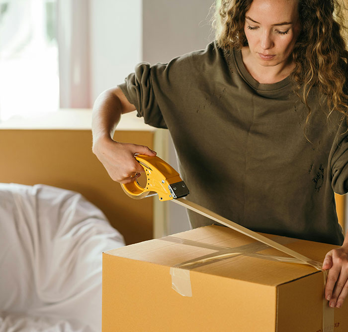 Young woman packing boxes, preparing to move out after frustration with responsibility for half-siblings.