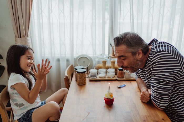 Older man and young girl celebrating with a cupcake, illustrating life moments of older people after divorce. - 3