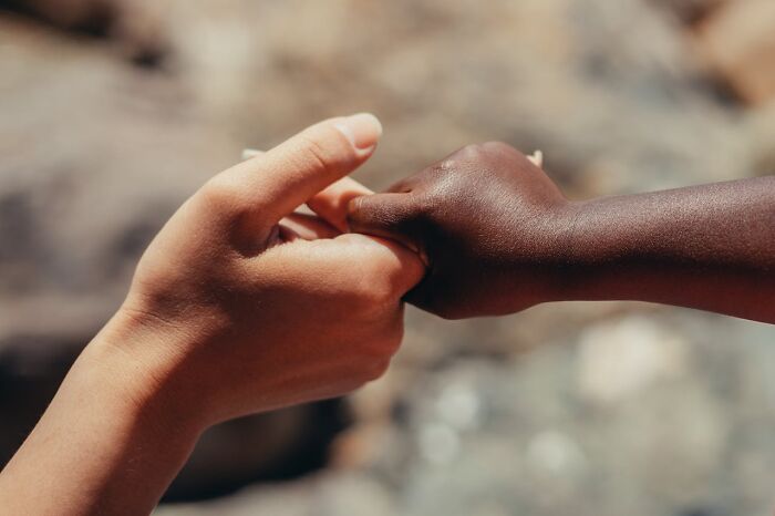 Two hands of different skin tones gently holding each other, symbolizing connection and support to stay hydrated.