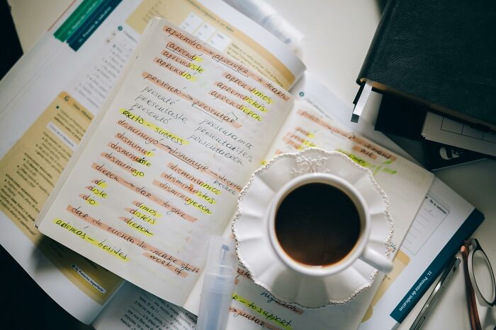Open book with highlighted words and definitions next to a cup of coffee, focusing on matching words to real definitions challenge.