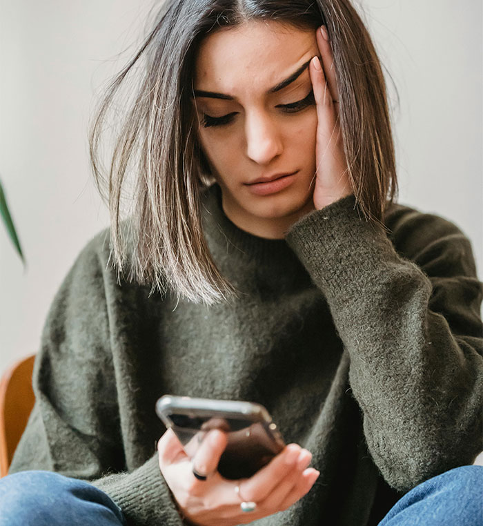 Young woman looking upset while holding smartphone, reflecting on a failed social media story test in relationship issues. - 10