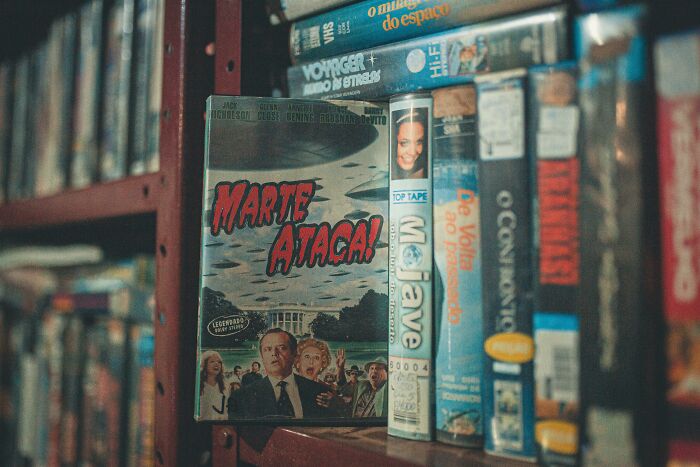 Close-up of vintage movie VHS tapes on a shelf, highlighting famous movie titles for IMDb memory challenge fans.