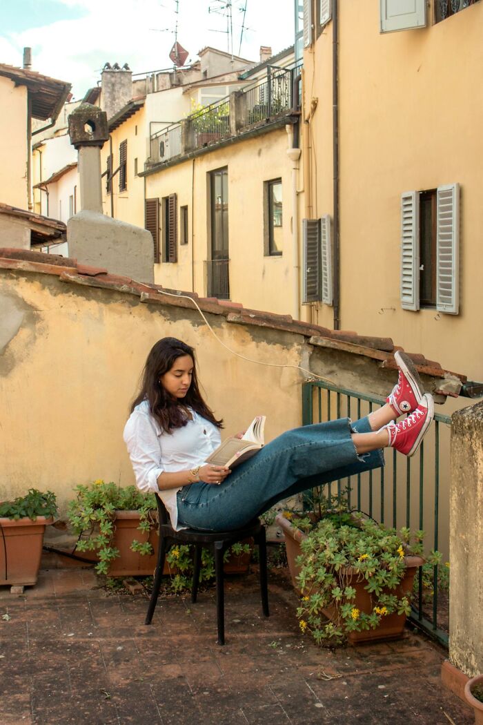 Young woman in casual clothes reading a book outdoors, demonstrating focus and relaxation while staying hydrated.
