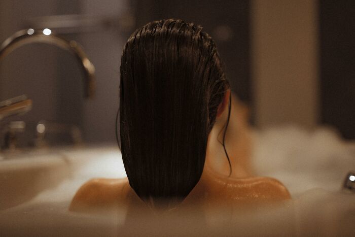 Person with wet hair in a bathtub, evoking themes related to people who deal with dead bodies and eerie details.
