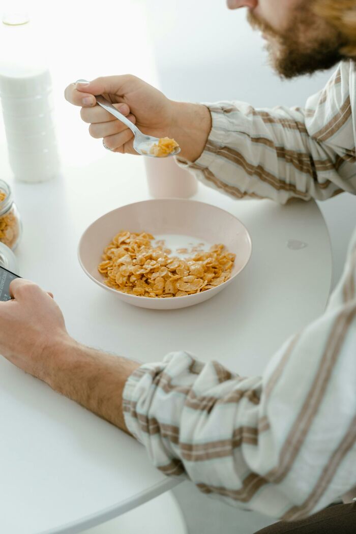 Older person eating cereal alone at a white table, reflecting on life after divorce and new beginnings. - 34