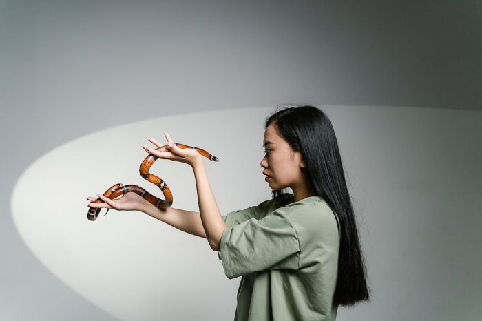 Woman in green shirt holding a snake carefully, illustrating survival tips that won't help in real-life situations.