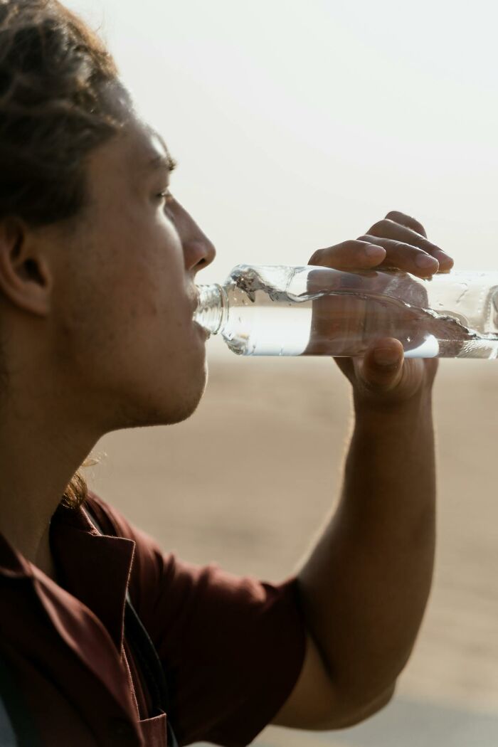 Person drinking water from a clear bottle outdoors illustrating survival tips that won't help you at all if followed
