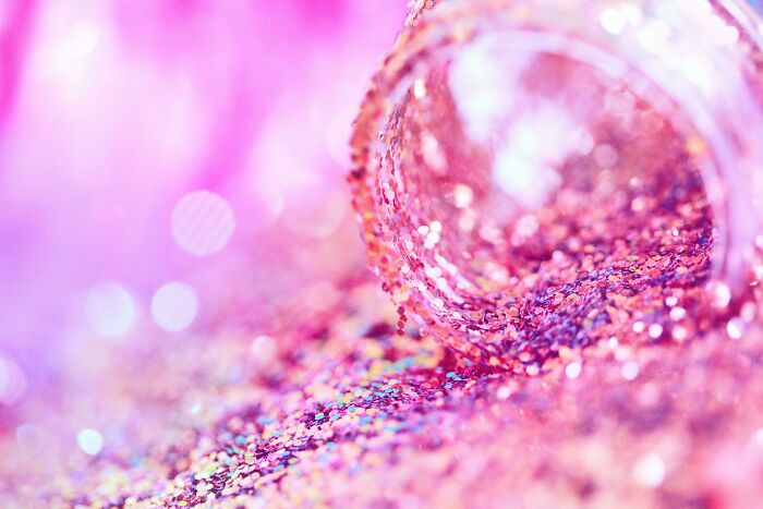 Close-up of spilled pink glitter creating a sparkling, colorful texture representing petty breakup drama imagery.
