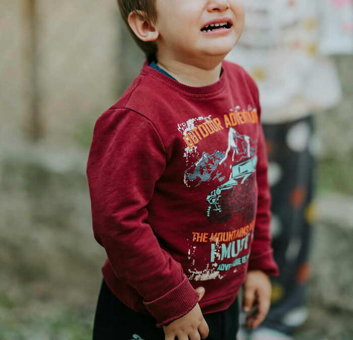 Crying child in a red sweatshirt, representing emotional reactions to disturbing things people overheard someone say.
