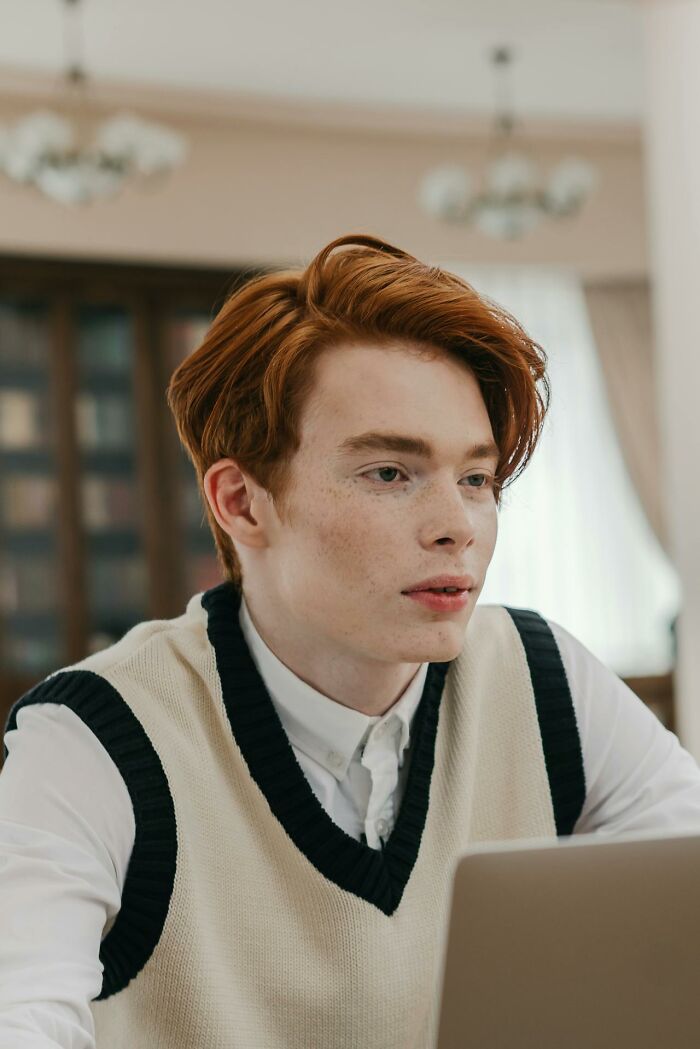 Young red-haired man working on laptop, focused in an office setting, illustrating stories of revenge on their bosses. - 9