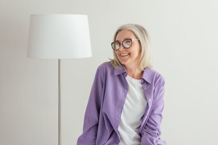 Older woman with glasses smiling and sitting indoors, reflecting on life after divorce in later years. - 7