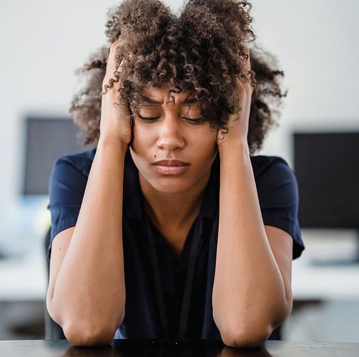 Stressed woman holding head in hands, showing emotional strain in a best friend sabotage relationship with boyfriend context.