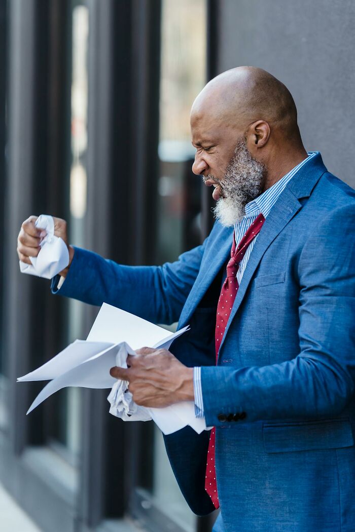 Angry man tearing papers in frustration outside, representing entitled patients demanding special treatment and care.