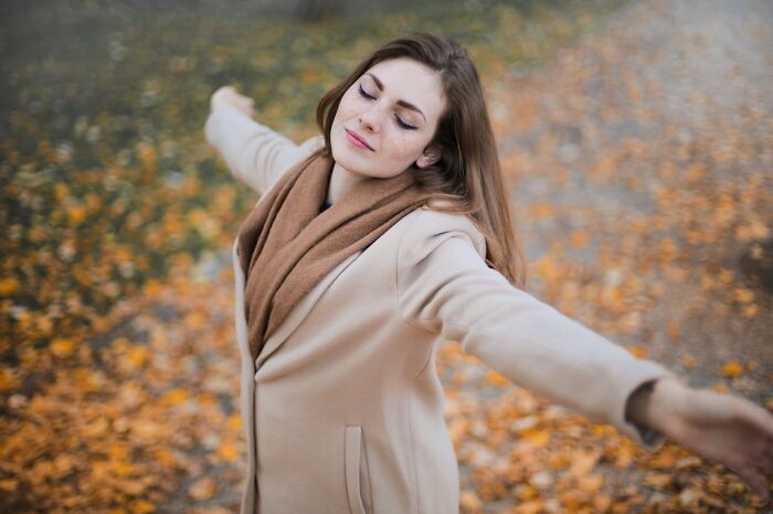 Older woman enjoying autumn outdoors, embracing new life and freedom after divorce, surrounded by fallen leaves. - 29