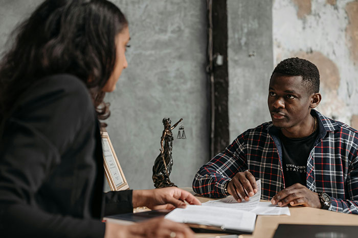 Man and woman discussing divorce papers at a desk with a Lady Justice statue between them in a legal office setting - 11