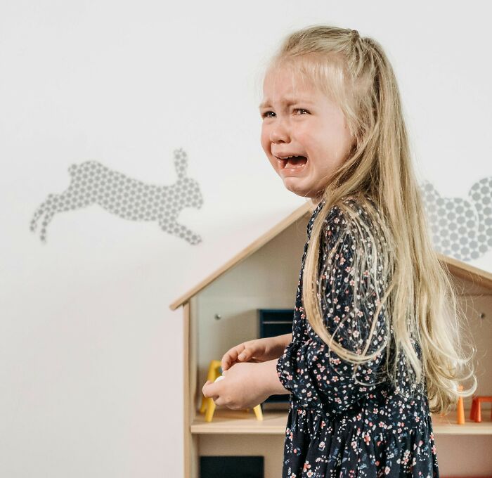 Crying young girl with long blonde hair in a floral dress, illustrating childhood trauma related to collecting toys. - 17