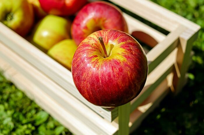 Bright red apples in a wooden crate outdoors, illustrating unusual and outrageous student names shared by a teacher.