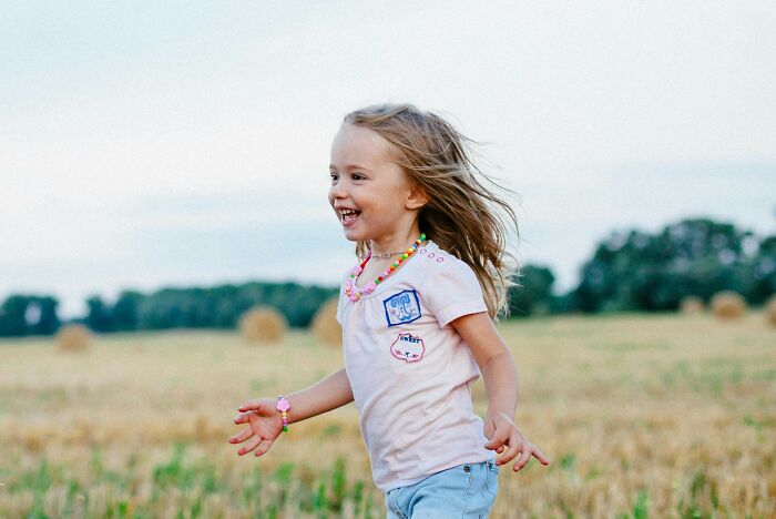 Young girl running happily in a field, illustrating the theme of truly outrageous student names shared by a teacher.