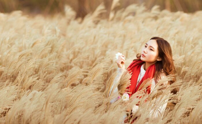 Young woman in a red scarf sitting in a field, reflecting peacefully as people share things that improved life. - 12