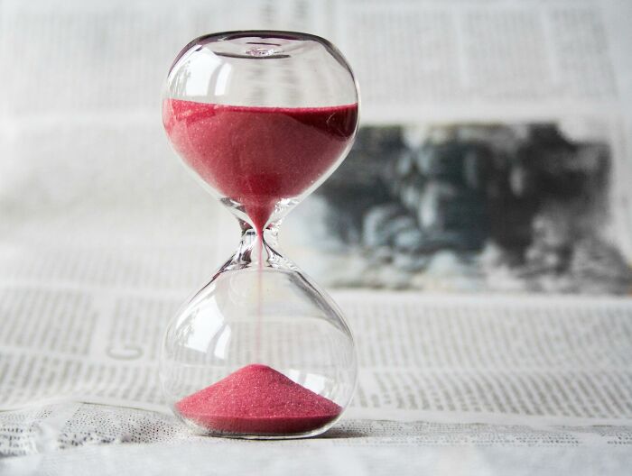 Clear hourglass with red sand flowing, symbolizing the timing of pickup lines in everyday life moments.