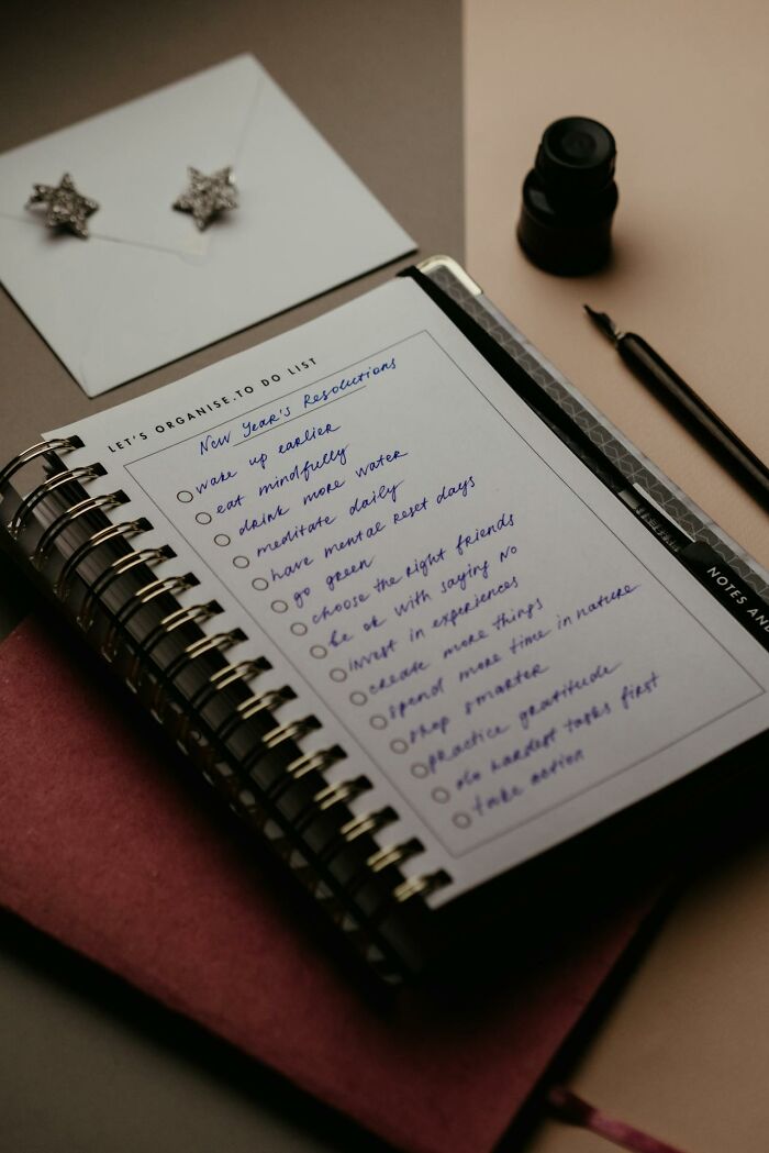 Spiral notebook with a handwritten to-do list featuring New Year’s resolutions about mindfulness and hydration.