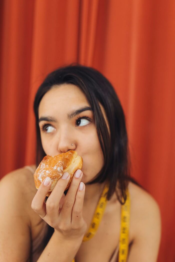 Young woman with a measuring tape around her neck, eating a donut and reflecting on toxic best friends. - 53