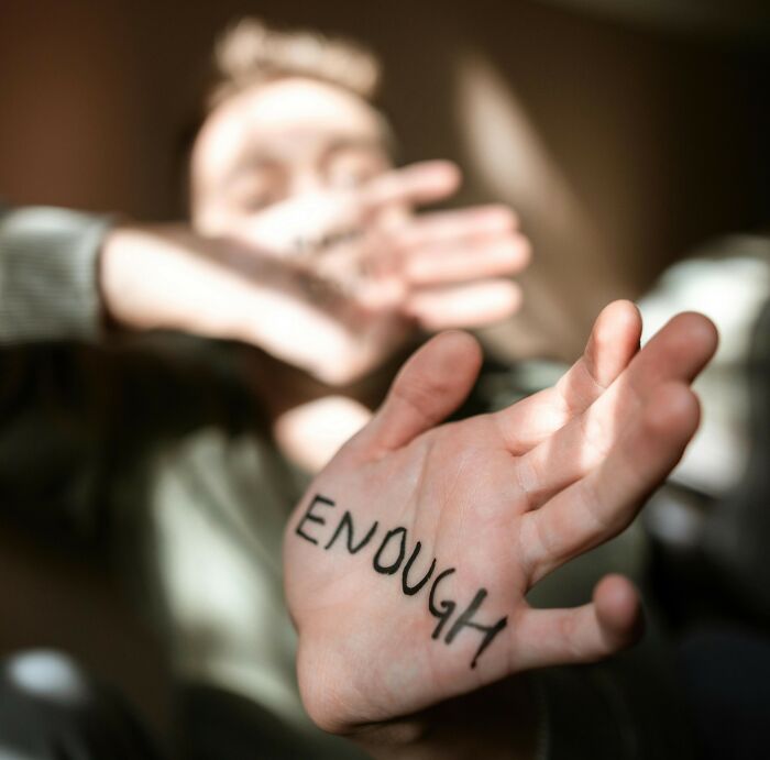 Person showing palm with the word enough written, illustrating people share things that improved life concept. - 3