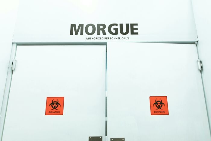 White morgue doors with biohazard signs, representing people who deal with dead bodies uncovering weird and terrifying details.