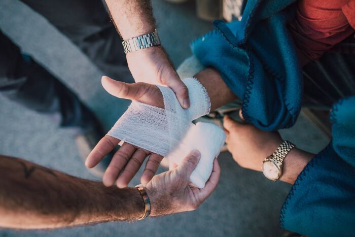 Person wrapping a bandage around a wrist, demonstrating survival tips for emergency first aid situations.