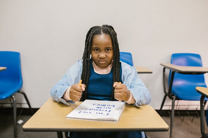 Young girl in classroom showing frustration while holding pencils, reflecting feelings about toxic best friends. - 56