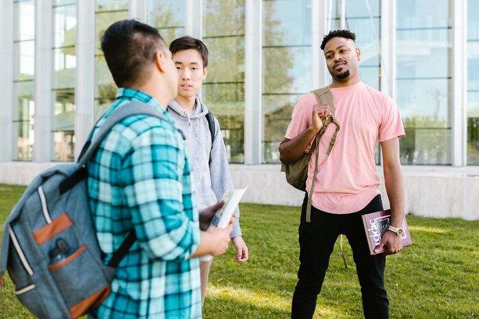 Three students chatting outside a school building, portraying a scene related to messed up school incidents. - 28