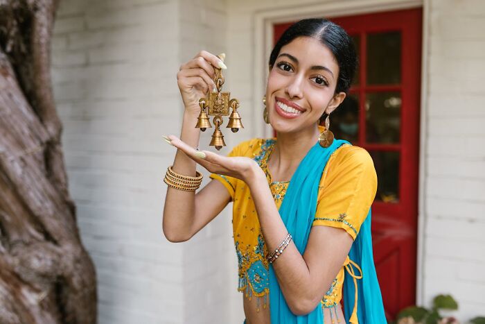 Young woman in traditional dress holding a decorative bell, illustrating bizarre facts about countries they’re from.