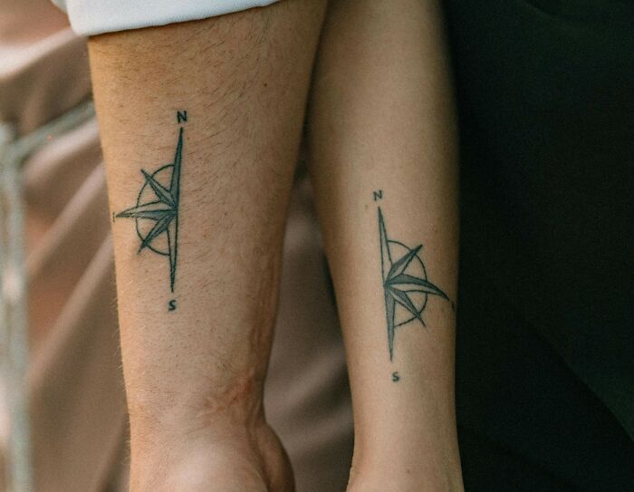 Close-up of matching compass tattoos on two forearms symbolizing couples and signs relationship days are numbered.