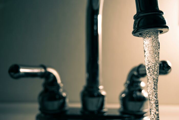 Close-up of water flowing from kitchen faucet highlighting water waste linked to global food waste crisis and environmental impact.