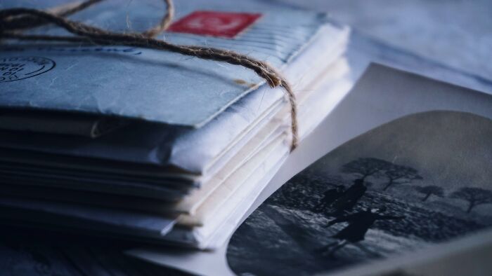 Stack of old letters tied with string next to a faded black and white photo representing interesting mysteries that still baffle people.