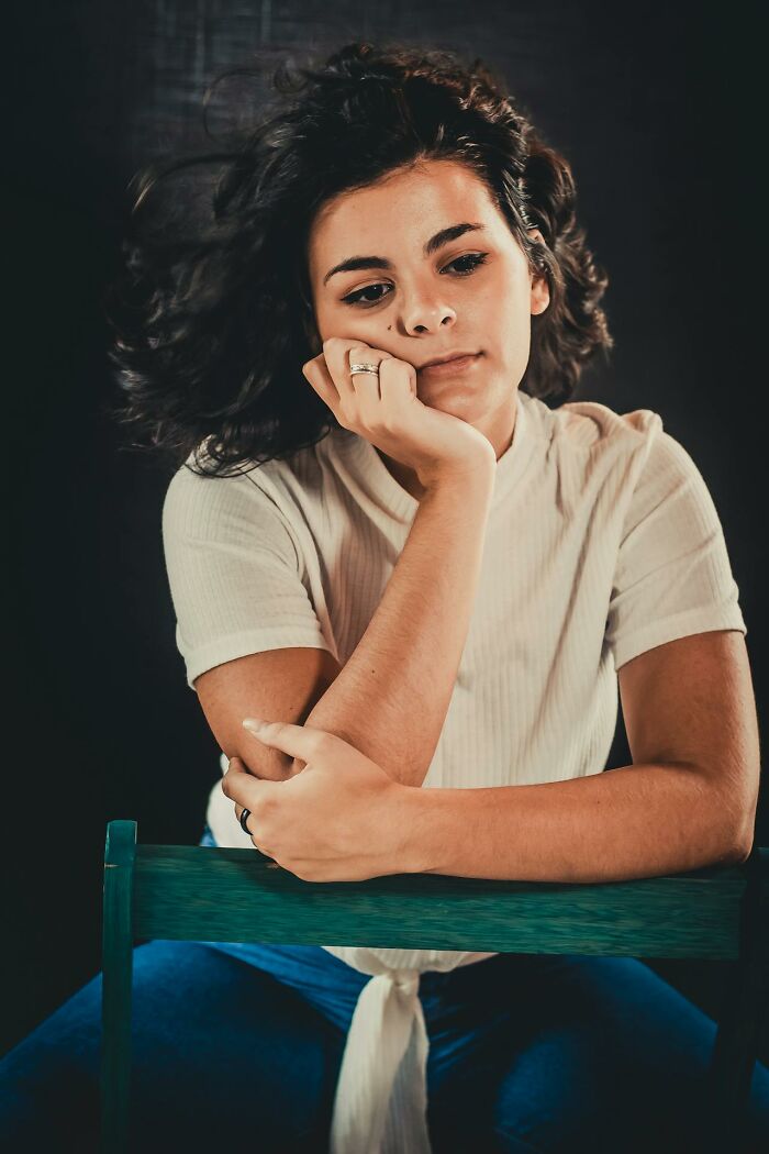Young woman sitting thoughtfully with hand on face, emphasizing the importance of stay hydrated for health and wellbeing.