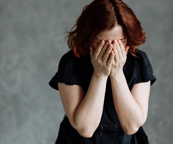 Young woman with red hair covering her face, expressing distress in a dramatic moment of a manipulative mom daughter story. - 13