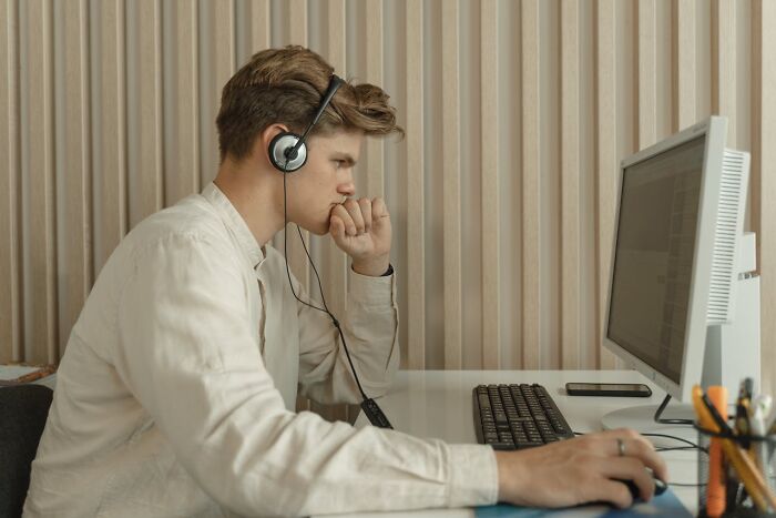Young man wearing headphones, focused on computer screen, illustrating signs of cheating red flags and relationship concerns. - 48